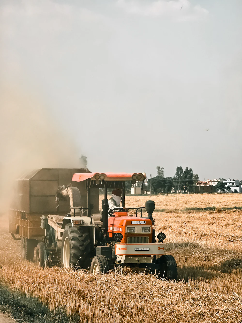 A tractor moving through a harvested field in Punjab.